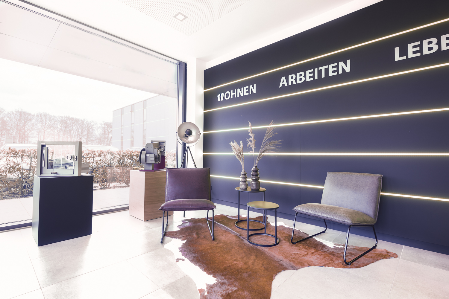 Ein wohnlicher Rückzugsort im Showroom, der Arbeits- und Lebensraum vereint. Die Lichtstreifen in der Wand erzeugen Tiefe und Dynamik.
